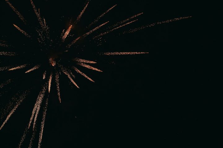 夜空にオレンジ色の光跡を広げる打ち上げ花火