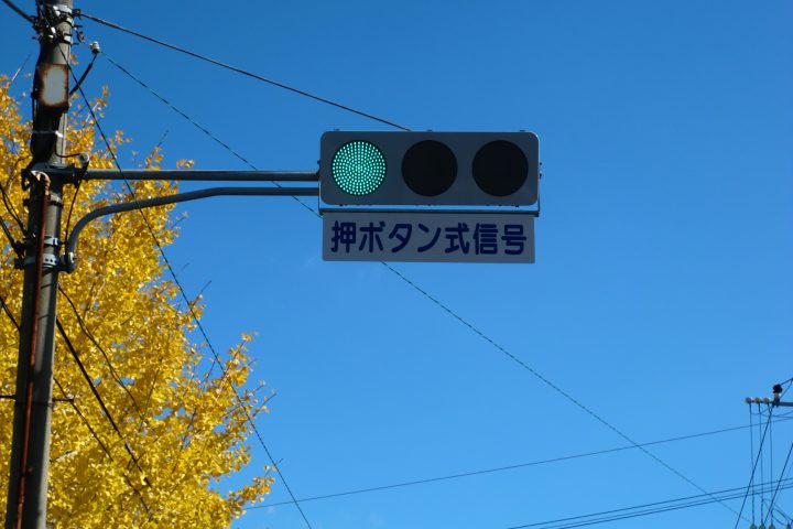 青空を背景に青緑色の灯火が点灯している熊本市の横型信号機