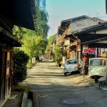 古い街並みの路地に小さな車が停まっている風景