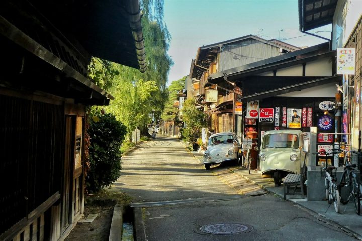 古い街並みの路地に小さな車が停まっている風景